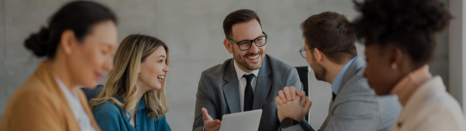 Grupo de compañeros de trabajo conversando alrededor de una mesa.