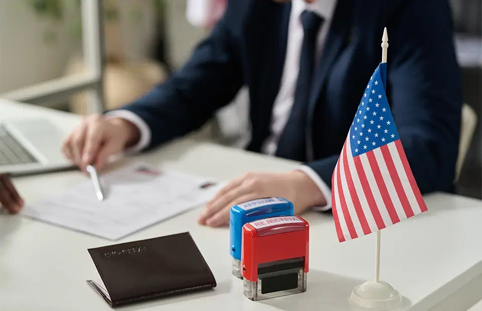 A U.S. passport, a pen, and a citizenship application form sit on a wooden table with part of the American flag visible in the background. Text overlay reads: “Do You Need a Lawyer to Apply for Citizenship?” A U.S. passport, a pen, and a citizenship application form sit on a wooden table with part of the American flag visible in the background. Text overlay reads: “Do You Need a Lawyer to Apply for Citizenship?”